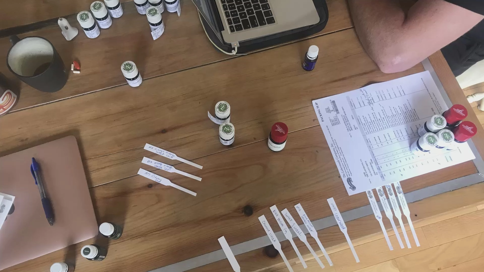 Fragrance sample strips and oil bottles on a wooden table